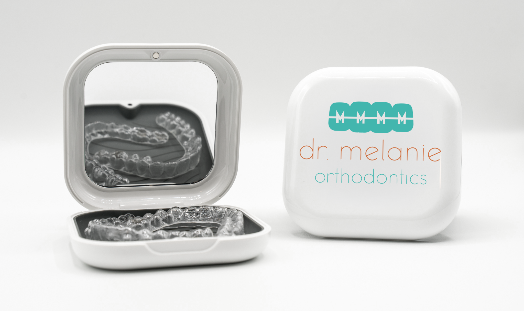 Open uLab aligner case with clear aligners beside a closed case featuring the Dr. Melanie Orthodontics logo.