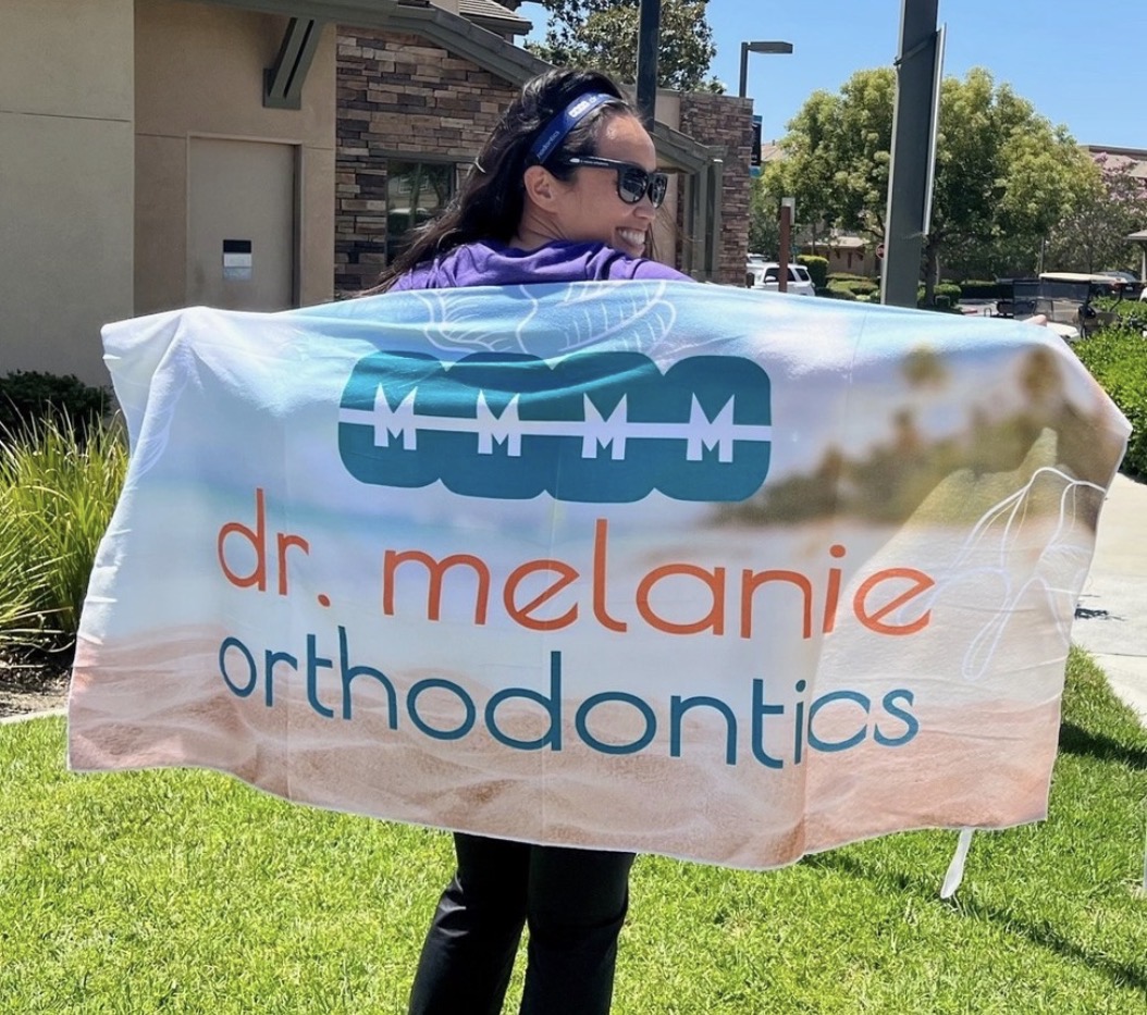 Person holding a towel featuring the Dr. Melanie Orthodontics logo.