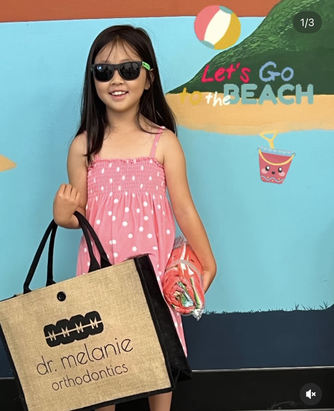 Child holding a tote bag featuring the Dr. Melanie Orthodontics logo.