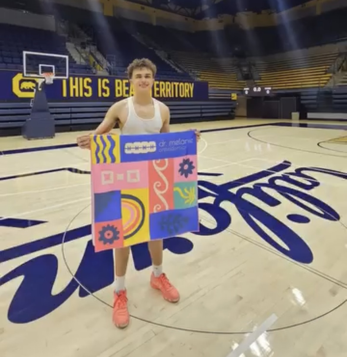 Person holding a colorful Dr. Melanie Orthodontics towel on a basketball court.